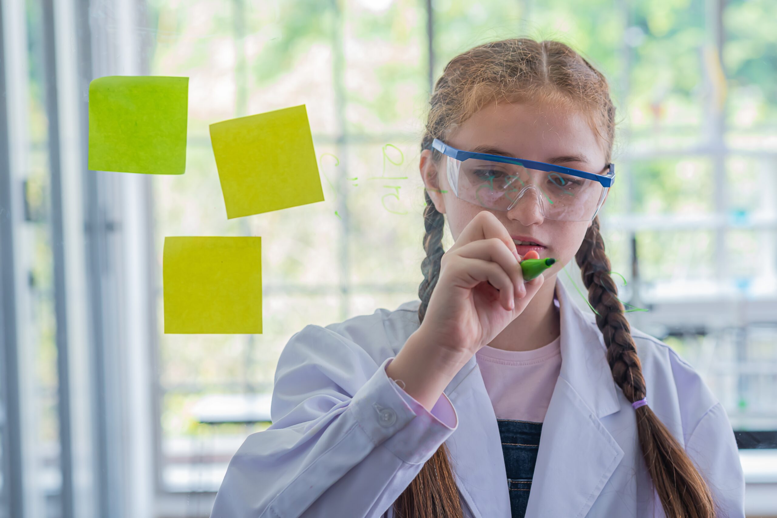 schoolgirl study science subjects and use marker write on board schoolgirl study science subjects and use marker write on board glass.